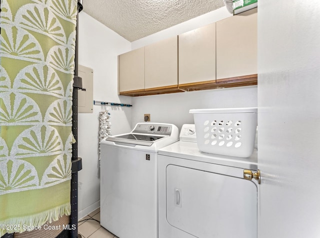 clothes washing area featuring light tile patterned floors, washing machine and clothes dryer, cabinets, and a textured ceiling