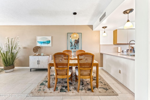 dining space featuring visible vents, a textured ceiling, baseboards, and light tile patterned floors