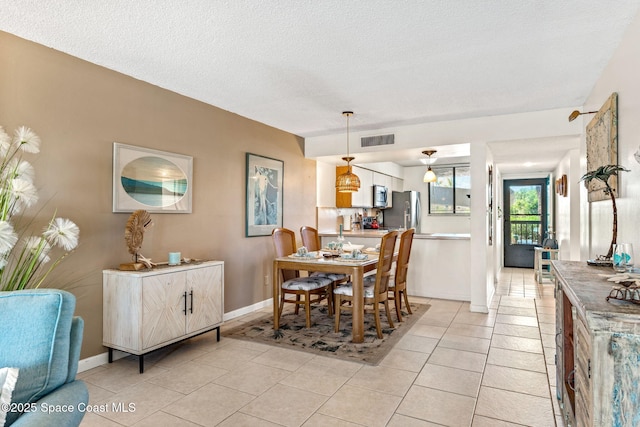 dining room featuring light tile patterned floors, a textured ceiling, visible vents, and baseboards