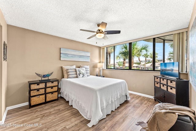 bedroom with a ceiling fan, a textured ceiling, baseboards, and wood finished floors