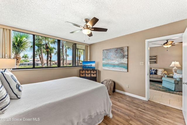 bedroom with a textured ceiling, ceiling fan, wood finished floors, and baseboards