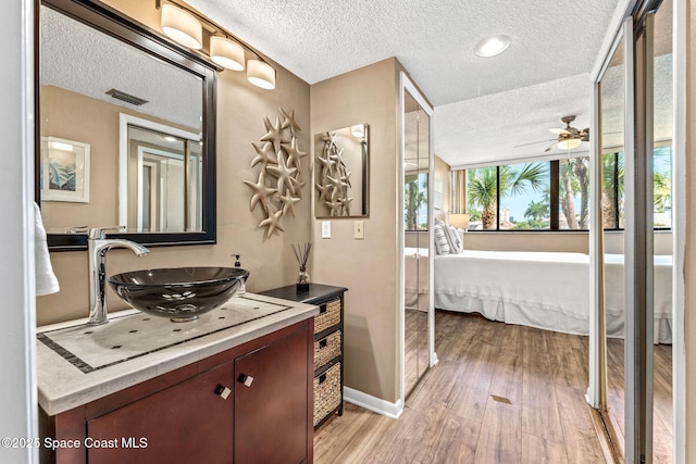 bathroom featuring hardwood / wood-style flooring, ceiling fan, vanity, and a textured ceiling