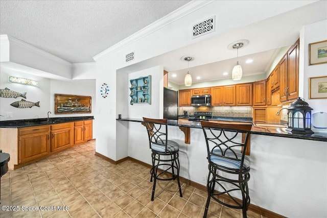 kitchen with decorative light fixtures, refrigerator, kitchen peninsula, electric range, and a breakfast bar area