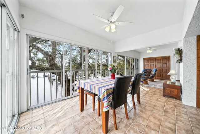 sunroom / solarium featuring ceiling fan and a water view