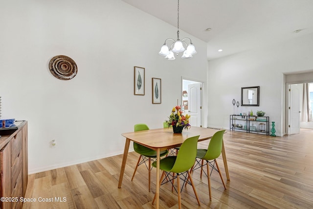 dining area with an inviting chandelier, light hardwood / wood-style flooring, and high vaulted ceiling