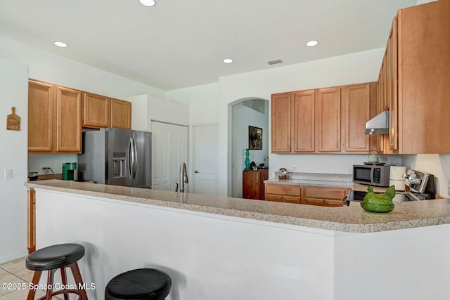 kitchen featuring extractor fan, appliances with stainless steel finishes, sink, a breakfast bar area, and kitchen peninsula