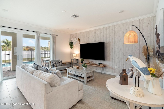 living room with light tile patterned floors, crown molding, and wooden walls