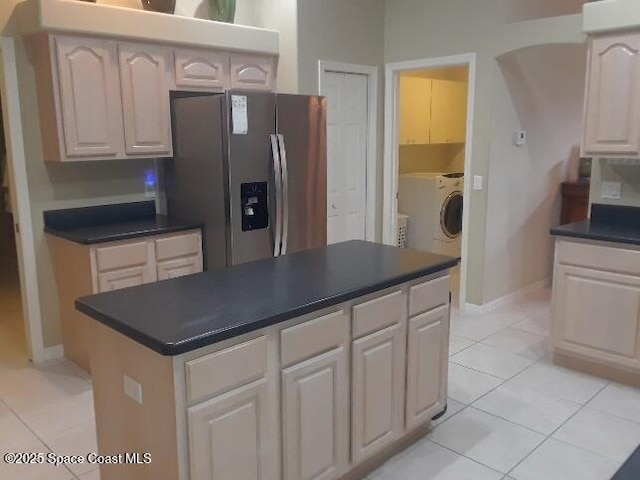 kitchen featuring light tile patterned flooring, stainless steel fridge, washer / clothes dryer, and a center island