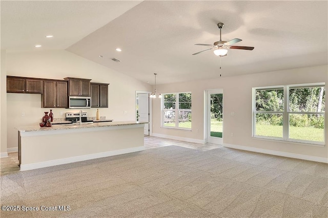 kitchen with light stone countertops, light colored carpet, appliances with stainless steel finishes, and lofted ceiling