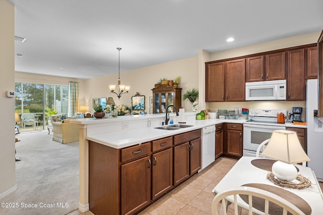 kitchen featuring white appliances, sink, hanging light fixtures, kitchen peninsula, and a chandelier