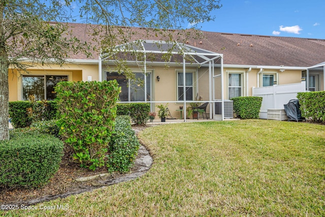 view of front of home featuring glass enclosure and a front yard