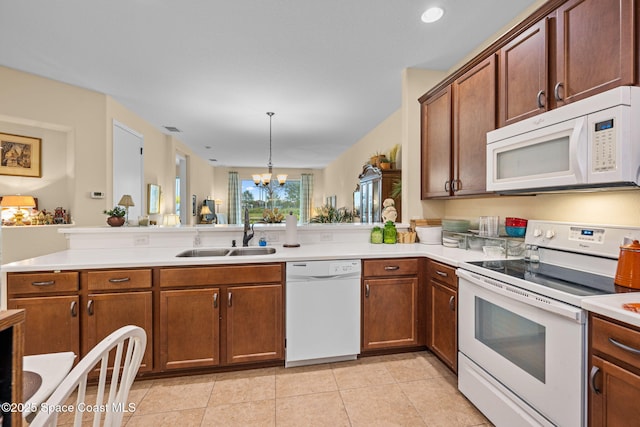 kitchen with kitchen peninsula, sink, white appliances, hanging light fixtures, and a chandelier