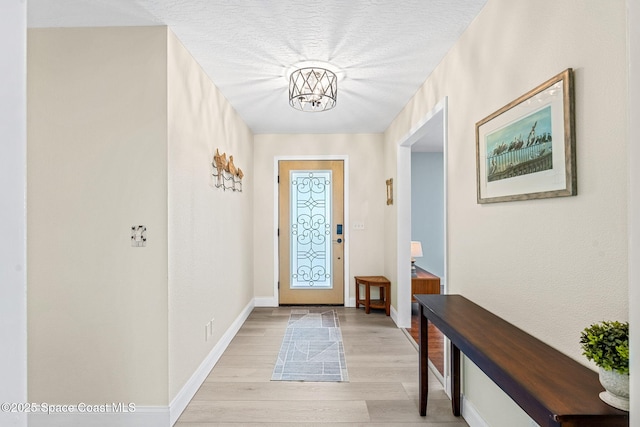 doorway to outside with a textured ceiling and light wood-type flooring