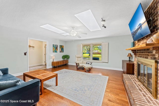 living room with hardwood / wood-style flooring, a fireplace, a skylight, and a textured ceiling