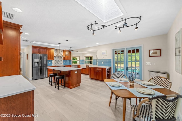 dining area with french doors, a skylight, light wood-type flooring, and a wealth of natural light