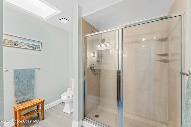 bathroom with hardwood / wood-style flooring, toilet, and a shower with shower door