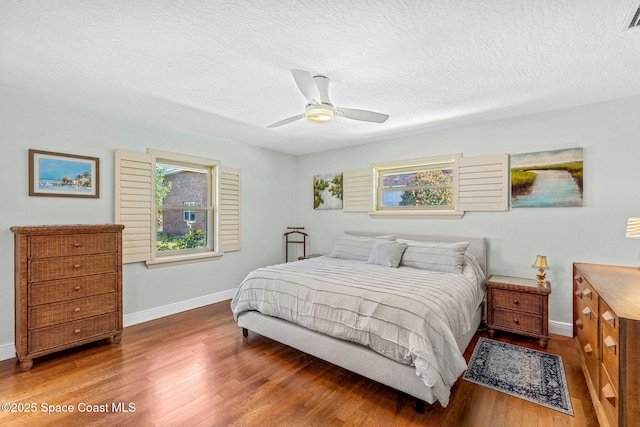 bedroom with hardwood / wood-style floors, a textured ceiling, and ceiling fan