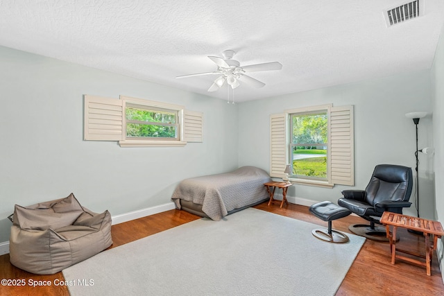 bedroom with hardwood / wood-style floors, a textured ceiling, and ceiling fan