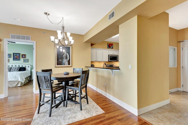 dining space with an inviting chandelier and light hardwood / wood-style flooring