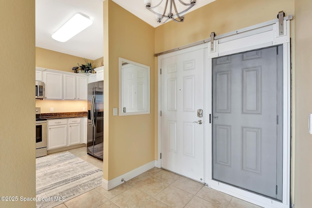 tiled foyer with a notable chandelier and a barn door