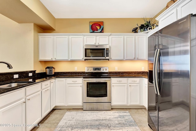 kitchen featuring white cabinetry, appliances with stainless steel finishes, sink, and dark stone countertops