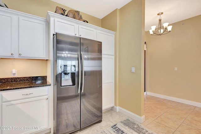 kitchen featuring white cabinetry, dark stone countertops, stainless steel fridge with ice dispenser, and light tile patterned floors