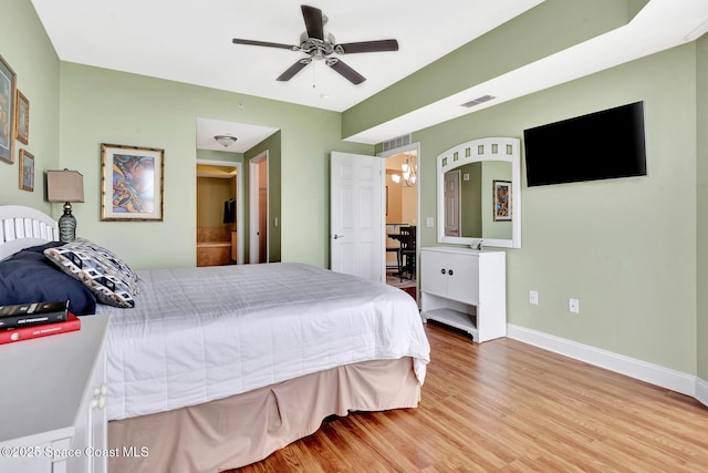 bedroom featuring hardwood / wood-style flooring and ceiling fan with notable chandelier