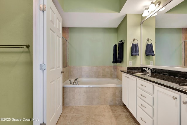 bathroom featuring a relaxing tiled tub, vanity, and tile patterned floors