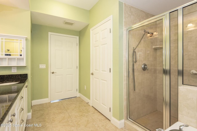 bathroom featuring walk in shower, vanity, and tile patterned flooring