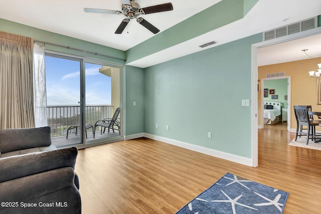 living area with hardwood / wood-style flooring and ceiling fan with notable chandelier