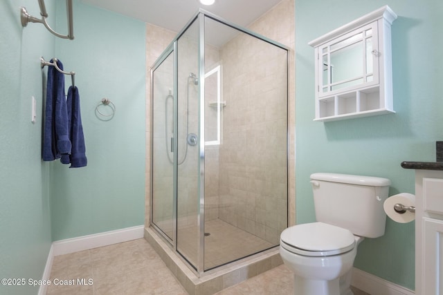 bathroom featuring tile patterned floors, toilet, and a shower with shower door