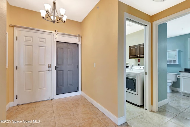 tiled foyer entrance featuring washer and clothes dryer, a barn door, and a chandelier