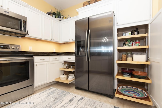 kitchen featuring stainless steel appliances, light tile patterned flooring, and white cabinets