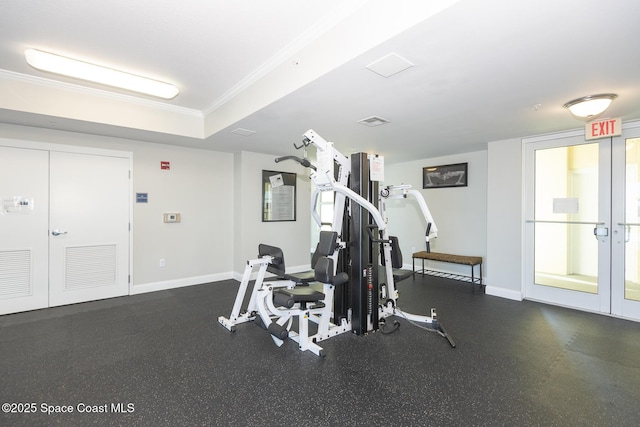 gym featuring a raised ceiling, ornamental molding, and french doors