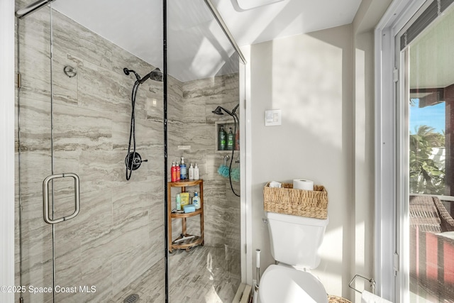 bathroom featuring a shower with door and toilet