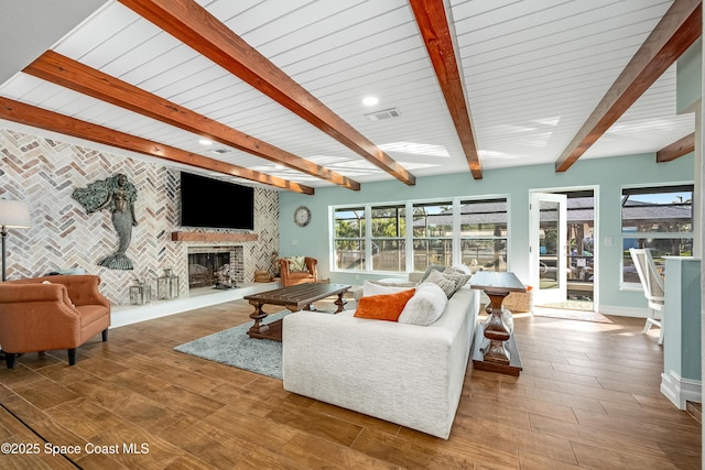 living room with a brick fireplace, hardwood / wood-style floors, and beamed ceiling