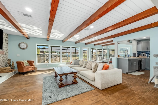 living room featuring wine cooler, sink, light hardwood / wood-style floors, and beam ceiling