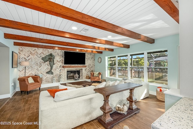 living room featuring dark wood-type flooring, a fireplace, and beamed ceiling