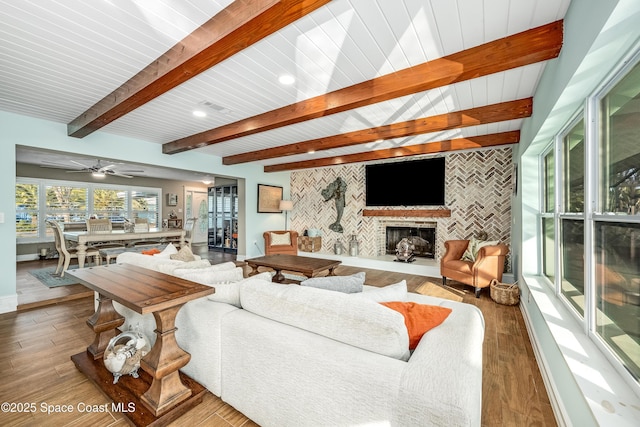 living room with beam ceiling, hardwood / wood-style flooring, and a large fireplace