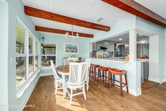 dining space with beamed ceiling, wood ceiling, light hardwood / wood-style flooring, and a notable chandelier