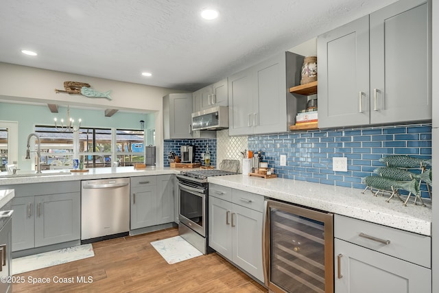 kitchen with appliances with stainless steel finishes, sink, gray cabinetry, wine cooler, and light hardwood / wood-style flooring