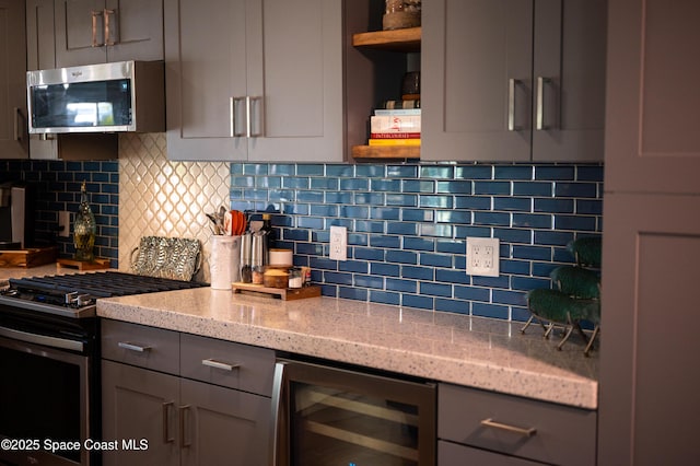 kitchen featuring light stone counters, appliances with stainless steel finishes, beverage cooler, and gray cabinetry