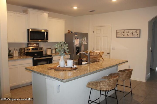 kitchen with white cabinets, appliances with stainless steel finishes, and a center island with sink