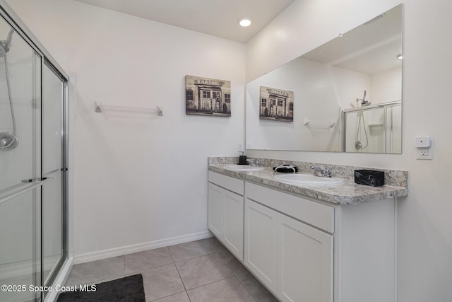 bathroom with a shower with shower door, vanity, and tile patterned flooring