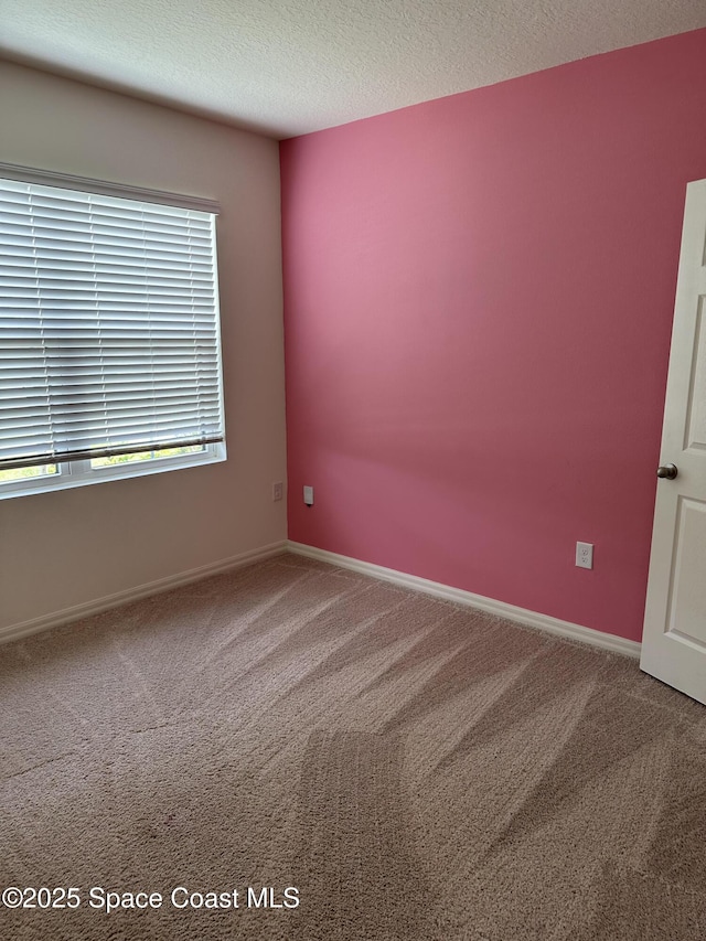 carpeted spare room with a textured ceiling and baseboards