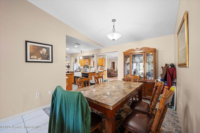 dining space with light tile patterned flooring and lofted ceiling