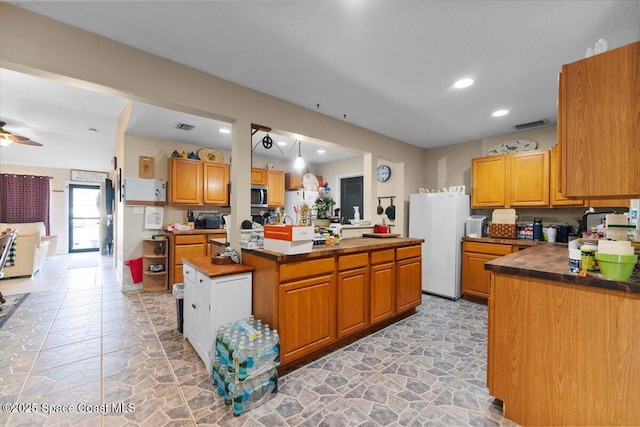 kitchen featuring ceiling fan, pendant lighting, white refrigerator, and a kitchen island