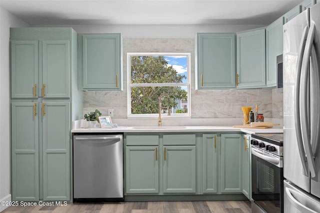 kitchen with sink, backsplash, stainless steel appliances, and green cabinetry