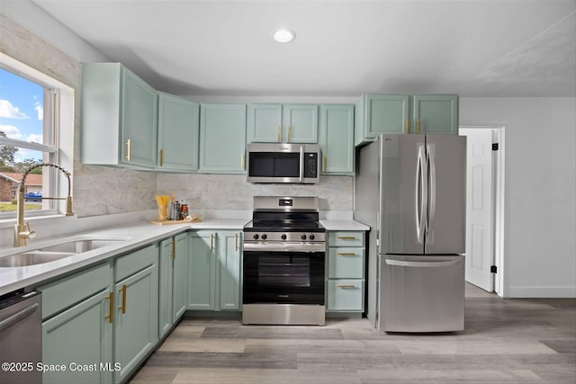 kitchen with sink, appliances with stainless steel finishes, light hardwood / wood-style flooring, and green cabinets