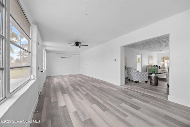 unfurnished living room featuring ceiling fan, light wood-type flooring, and a healthy amount of sunlight